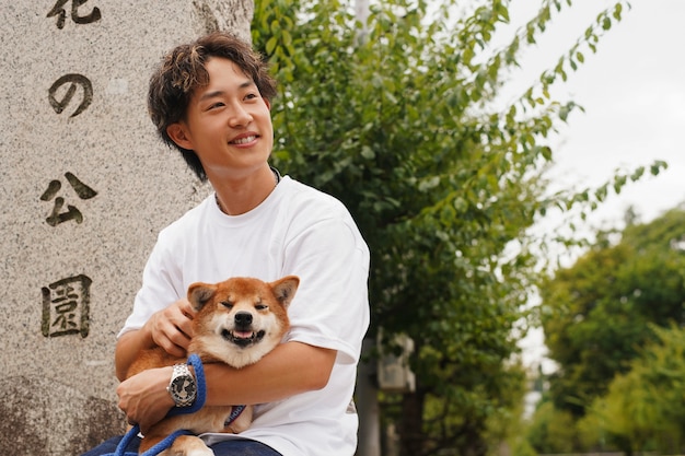 Gratis foto aziatische man met zijn shiba inu-hond buitenshuis