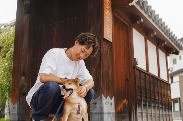 Gratis foto aziatische man met zijn shiba inu-hond buitenshuis