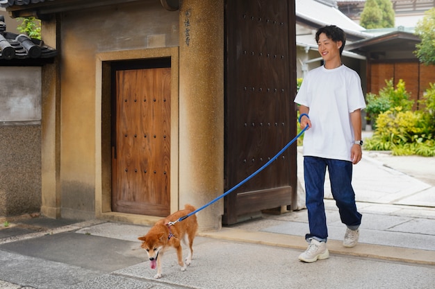 Gratis foto aziatische man met zijn shiba inu-hond buitenshuis