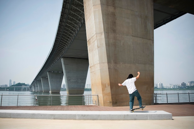 Aziatische man skateboarden in de stad buiten