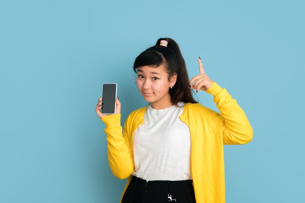 Aziatische tiener portret geïsoleerd op blauwe ruimte. Mooi vrouwelijk donkerbruin model met lang haar