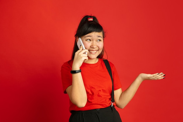 Aziatische tiener portret geïsoleerd op rode ruimte. mooi vrouwelijk donkerbruin model met lang haar in informele stijl