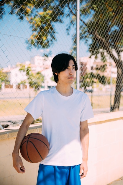 Gratis foto aziatische tienerstudent klaar voor basketbalspel