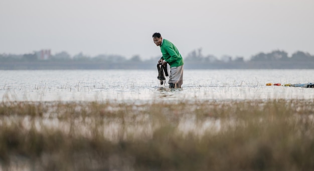 Gratis foto aziatische visser die in het water staat en visnet om te vissen in de rivier in de vroege ochtend, kopieer ruimte