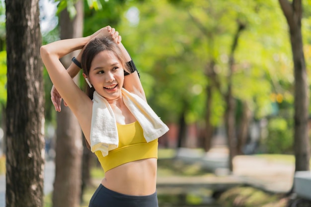 Aziatische vrolijke jonge volwassene aantrekkelijk en sterke ochtend die zich uitstrekt voordat ze in het park rent sportconcept gezonde levensstijl jonge fitnessvrouw die zich uitstrekt voordat ze op het park loopt