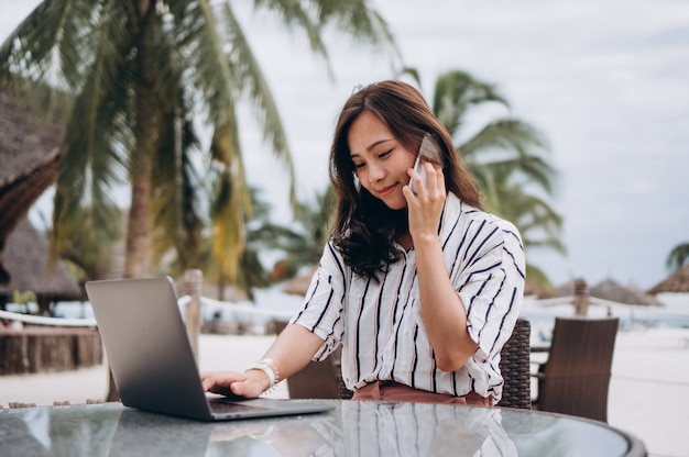 Aziatische vrouw die aan laptop op een vakantie werkt