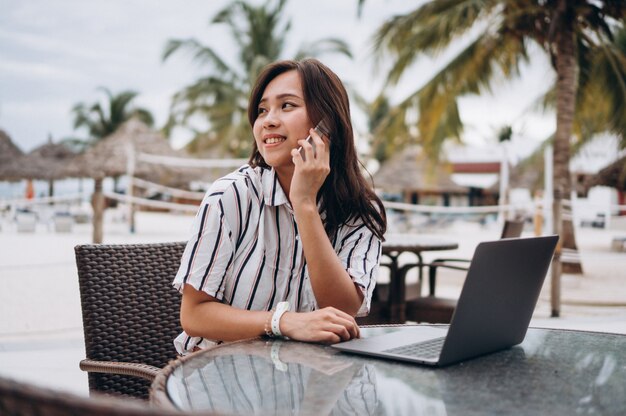 Aziatische vrouw die aan laptop op een vakantie werkt