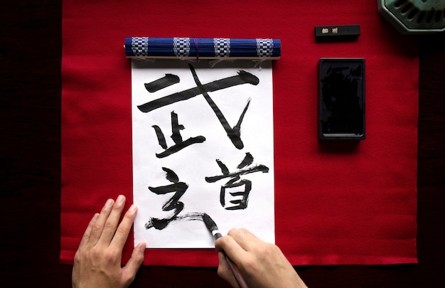 Aziatische vrouw die binnen Japans handschrift oefent
