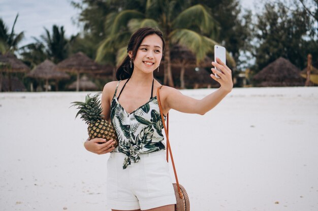 Aziatische vrouw die op de telefoon bij het strand spreekt