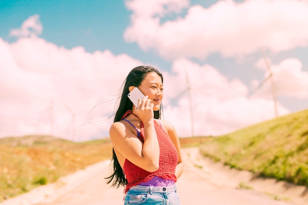 Aziatische vrouw die op telefoon in platteland spreekt