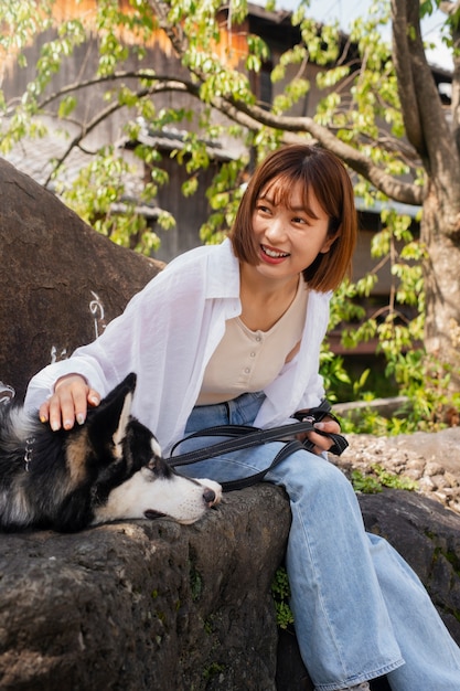 Gratis foto aziatische vrouw loopt met haar husky hond buiten