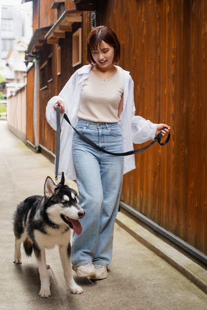 Gratis foto aziatische vrouw loopt met haar husky hond buiten