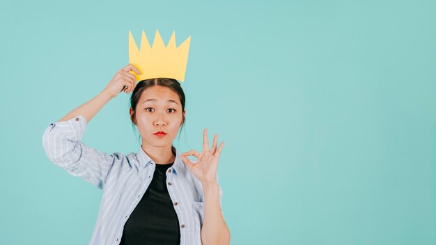 Aziatische vrouw met document kroon die ok gesturing