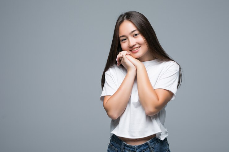 Gratis Foto aziatische vrouw poseert en kijkt weg over een grijze achtergrond
