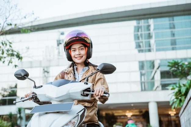 Aziatische vrouw rijdt op een motorfiets met een helm op straat Premium Foto