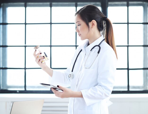Aziatische vrouwelijke arts, vrouwenspecialist met digitale tablet en pillen