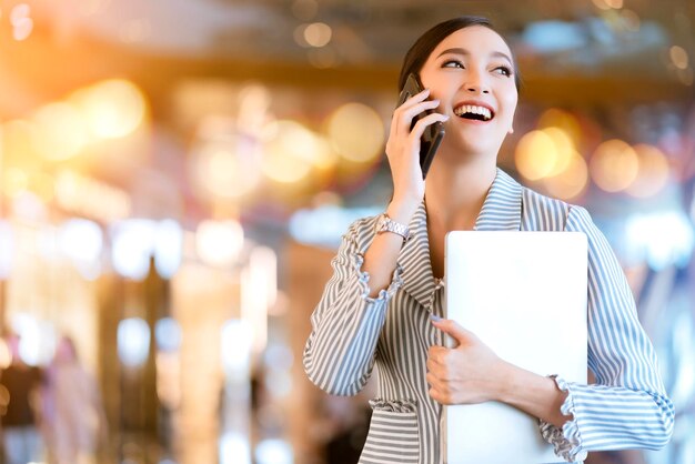 Aziatische vrouwelijke bedrijfseigenaar handcommunicatie met smartphone en laptop bedrijfstechnologie met wazige winkel bokeh achtergrond