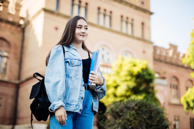 Aziatische vrouwelijke hogeschool of universiteitsstudent. Gemengd ras Aziatisch jong vrouwenmodel dat schooltas draagt.