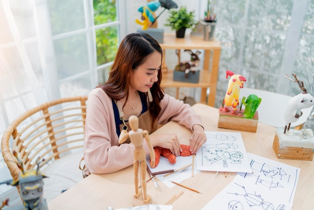 Aziatische vrouwelijke kunstenaar een arttoys kleisculptuur brengt een weekenddag door voor haar hobby klei scuplt definieert de vorm van het gezicht op de juiste manier terwijl ze het kleistandbeeld thuis maakt studio casual levensstijl thuis