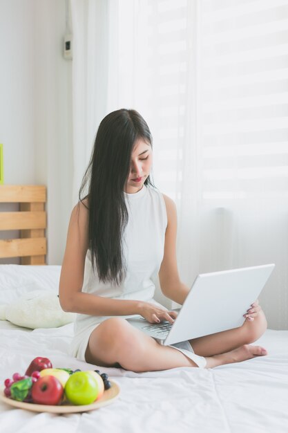 Aziatische vrouwen spelen met laptop in de slaapkamer