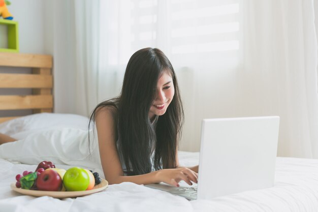 Aziatische vrouwen spelen met laptop in de slaapkamer