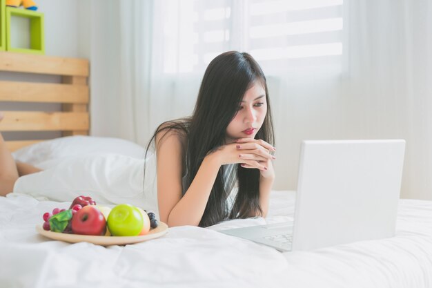 Aziatische vrouwen spelen met laptop in de slaapkamer