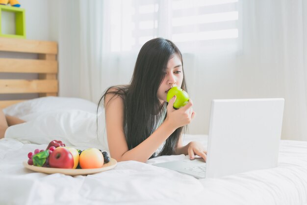 Aziatische vrouwen spelen met laptop in de slaapkamer