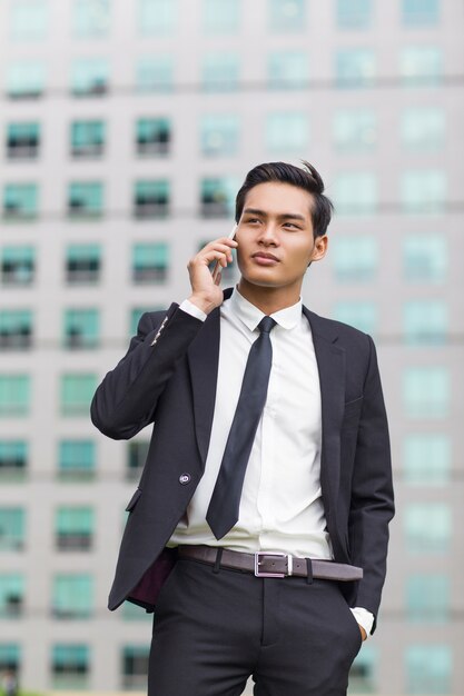 Aziatische zakenman die op telefoon buiten belt