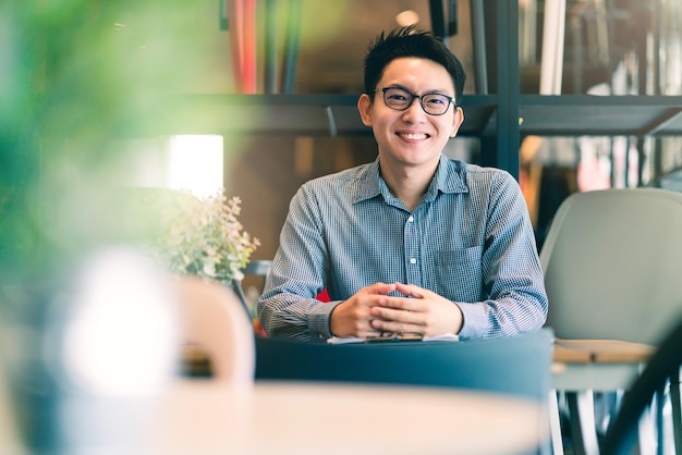 Aziatische zakenman startup bedrijf ondernemer zit glimlach met geluk in nieuwe winkel winkel kantoor achtergrond zakelijke ideeën concept