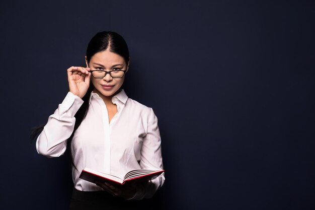 Aziatische zakenvrouw die een bril aanraakt en een notitieboekje vasthoudt