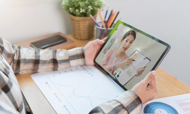 Aziatische zakenvrouw die op afstand werkt vanuit huis en webinar voor virtuele videoconferentievergaderingen met collega's uit het bedrijfsleven. sociale afstand thuis kantoor concept.