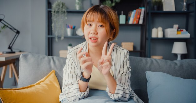 Aziatische zakenvrouw met behulp van laptop praten met collega's over plan in videogesprek tijdens het werken vanuit huis in de woonkamer