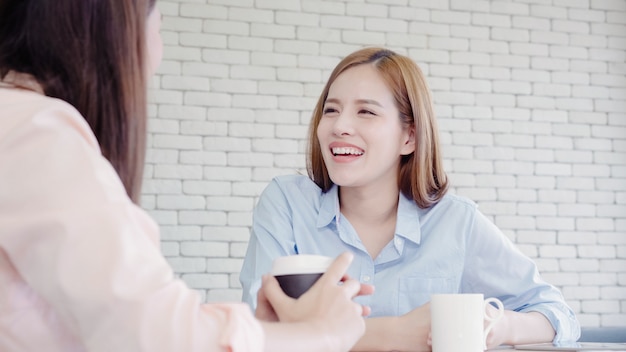 Aziatische zakenvrouwen genieten van het drinken van warme koffie, discussiëren over werk en chit chat roddels