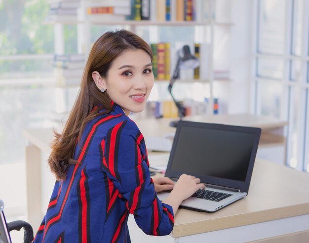 Aziatische zelfverzekerde vrouw laat haar hand op het toetsenbord van de laptop rusten en keert terug