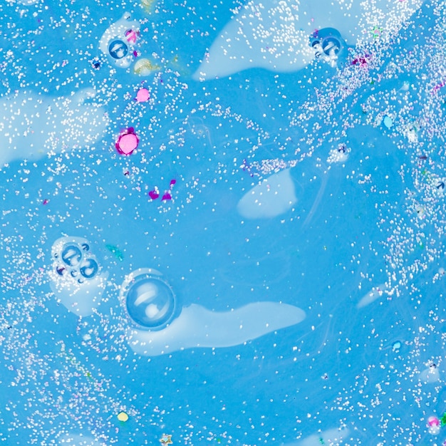 Azuurblauwe vloeistof met kleurrijke stukjes