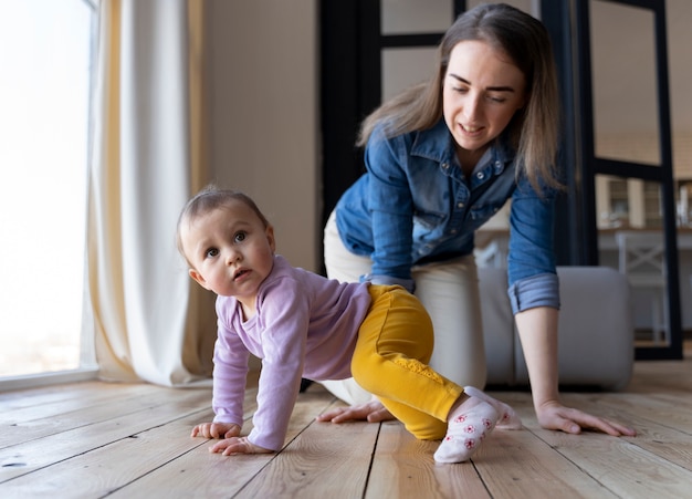 Gratis foto baby kruipt met de hulp van zijn moeder