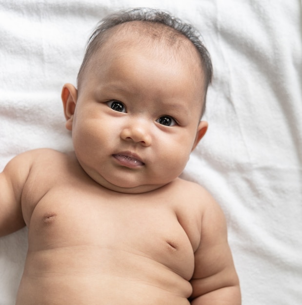 Baby liggend met zijn gezicht omhoog op een wit bed