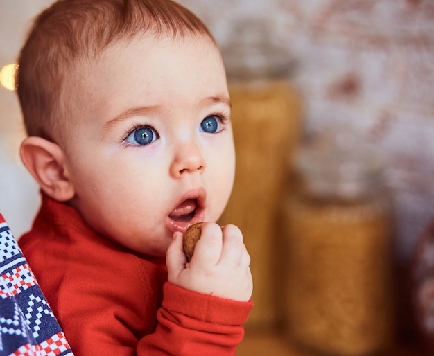 Gratis foto baby met blauwe ogen eet een noot