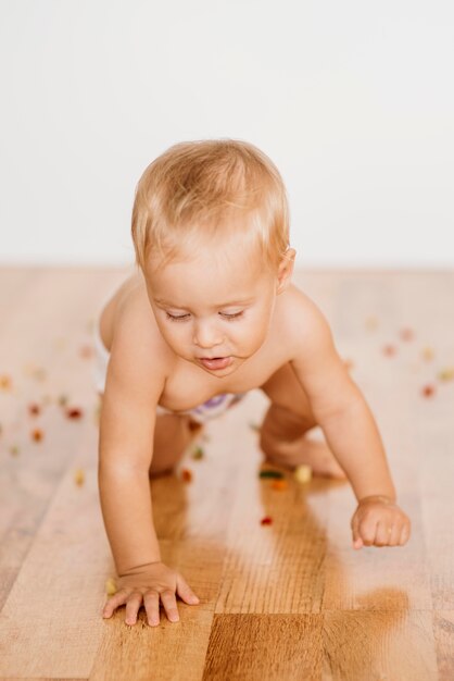 Baby met eten om hem heen op de grond