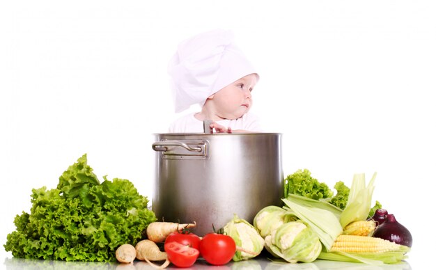 Baby met hoed's chef-kok omringd door groenten