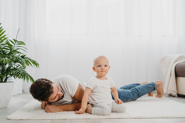 Gratis foto baby staande op de vloer thuis met vader