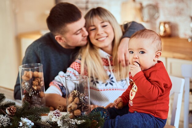 Baby zit aan tafel, zijn ouders knuffelen