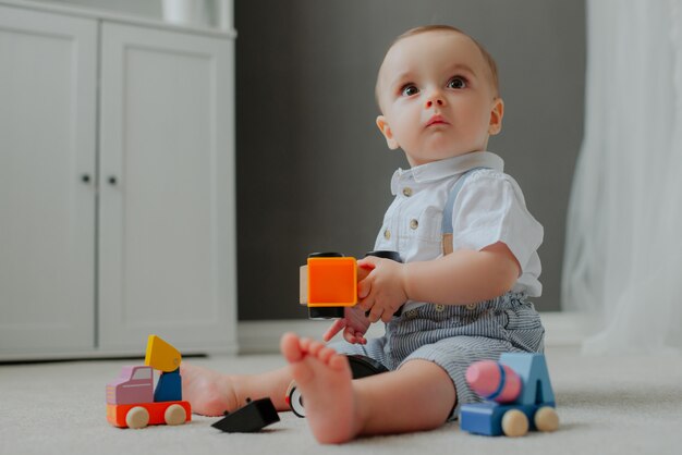 Baby zittend op de vloer met speelgoed en verrast.