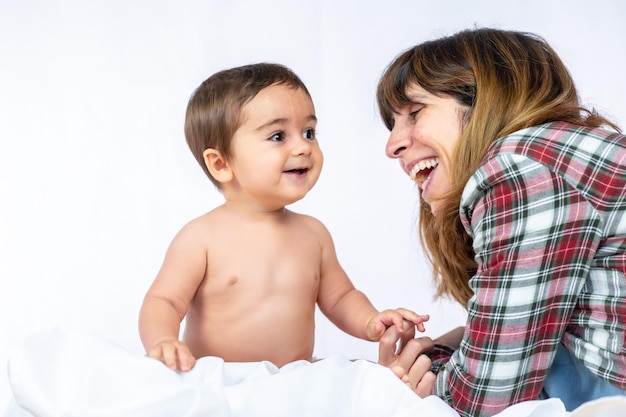 Babyjongen in een studio met een witte achtergrond, acht maanden oude blanke pasgeborene zit en speelt met zijn moeder