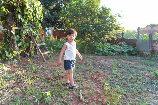 Babyjongen met blauwe ogen die in de achtertuin speelt