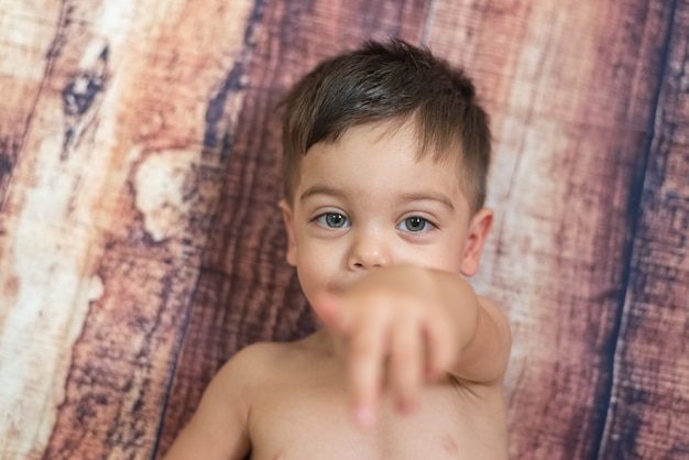 Babyjongen met blauwe ogen die op houten muur liggen