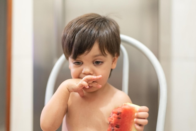 Babyjongen met blauwe ogen die watermeloen eet