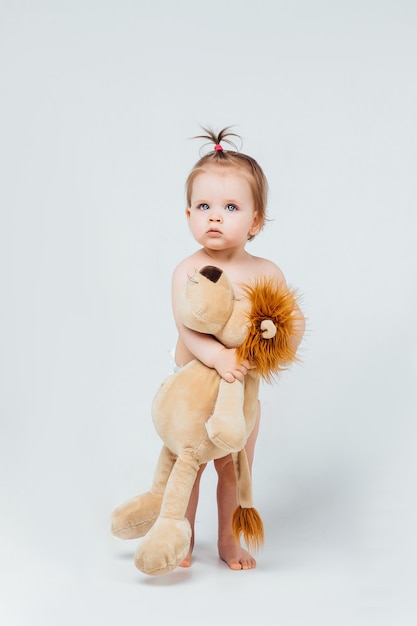 Gratis foto babymeisje het spelen met haar leeuwstuk speelgoed dat op witte muur wordt geïsoleerd.