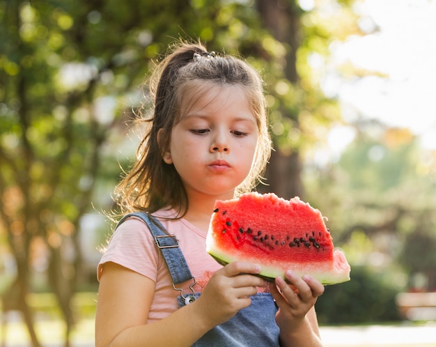 Babymeisje in aard die een watermeloenplak hebben
