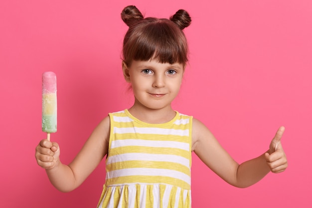 babymeisje jongen eten van ijs, ziet er blij uit en duimen opdagen